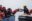 Rettungssituation mit einem Crewmitglied von SOS Humantiy, das Flüchtlingen auf einem Boot Rettungswesten reicht.