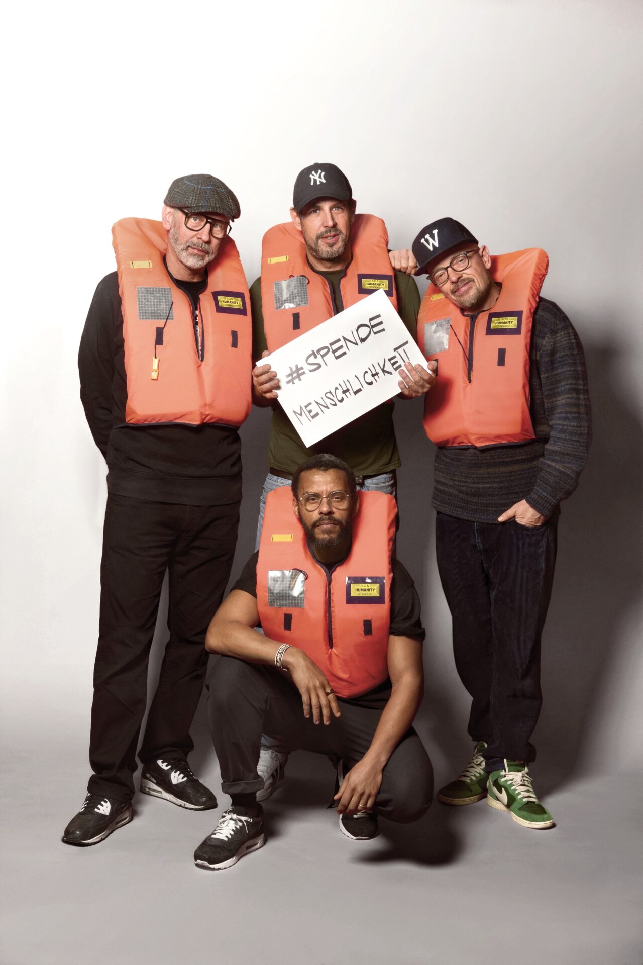 Die Band "Die Beginner" halten gemeinsam ein Schild, auf dem steht "Spende Menschlichkeit".